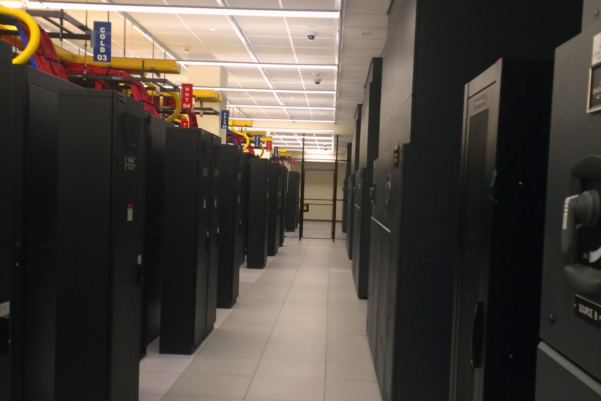 The production equipment is organized on strict hot/cold aisled. CRAH units pressurize the access floor for distribution. Return is by ceiling plenum to CRAH return snorkels